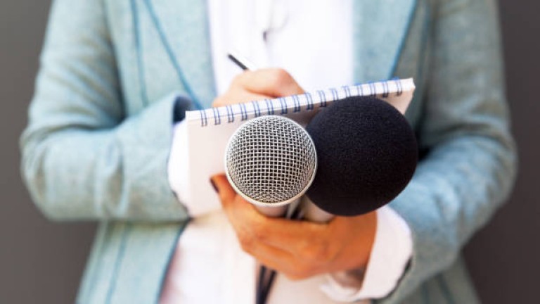 Female reporter at press conference, writing notes, holding microphone Female reporter at press conference, writing notes, holding microphone